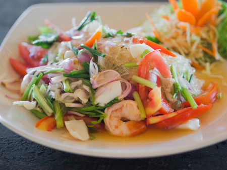 Traditional Thai cuisine. Rice noodle salad, fresh vegetables and herbs and seafood on a plate in a cafe.の写真素材
