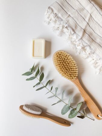 Body brush with wooden handle, pumice, wicker box, white towel and a piece of soap on white background. top view.の写真素材