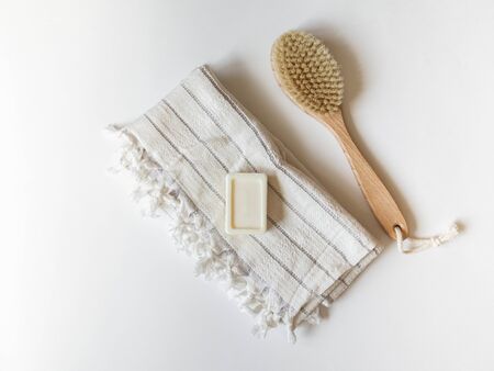Body brush with wooden handle, white towel and a piece of soap on white background.の写真素材