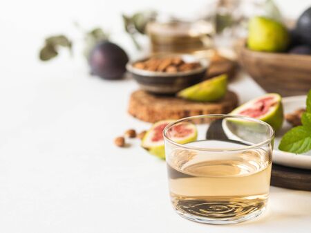 Glass of white wine, figs and almonds on white background. Still life of holidays seasonal harvesting fall autumn concept. Copy spaceの写真素材