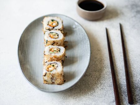 Sushi roll with sea bass and cucumbers with tuna chips on oval ceramic plateの写真素材