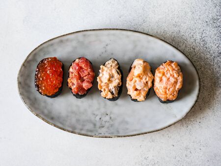 Variety gunkans with salmon, shrimp, tuna, mussels, red caviar on oval ceramic plate. Top viewの写真素材