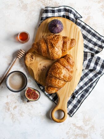 Breakfast flat lay with croissants on a wood cutting board, figs and espresso coffee on grey background, top view,の写真素材
