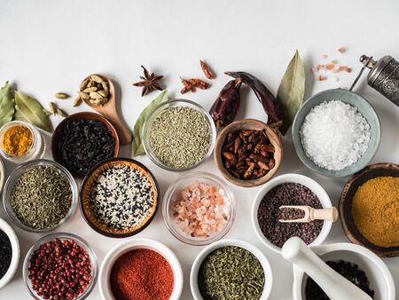 Various dry spices flat lay in small bowls on white wood background. Top view,の写真素材