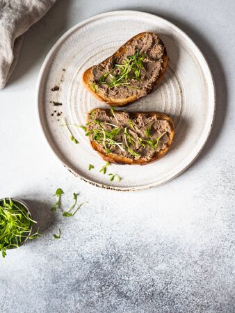 Two toasts chicken rillettes (pate) on white bread with sprouts on white plate on a lightの写真素材
