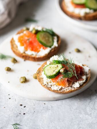 Several sandwiches on rye bread with cream cheese, salmon, fresh cucumber and spices.の写真素材