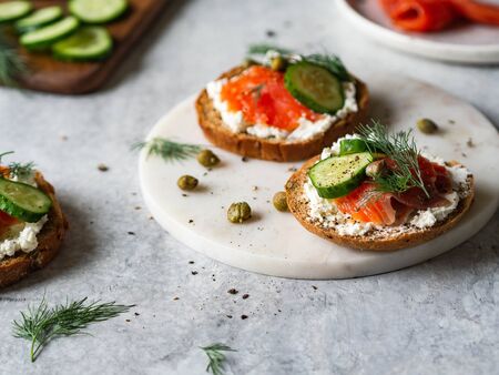 Several sandwiches on rye bread with cream cheese, salmon, fresh cucumber and spices.の写真素材