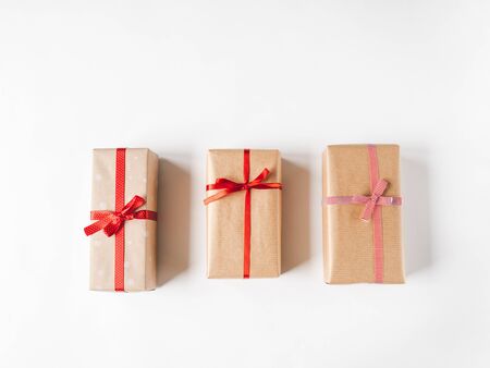 Christmas composition with gifts in craft paper and red decor tapes on a white background.