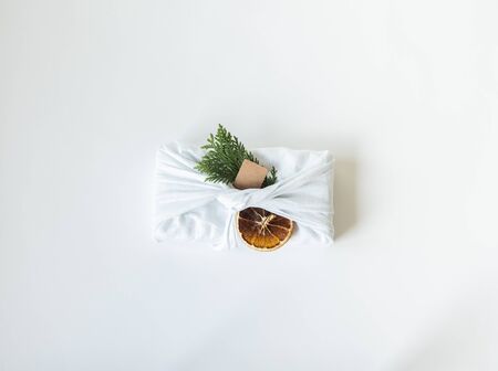 Eco-friendly fabric reusable gift packaging with fir branch, paper tag and dry orange slice....