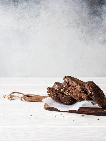 Whole grain rye bread with various seeds sliced slices on a wooden board on a gray background. Copy spaceの写真素材