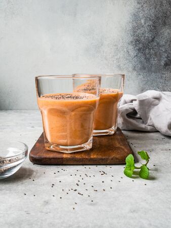 Two glasses of fresh healthy carrot smoothie with chia seeds on grey background on grey backgroundの写真素材