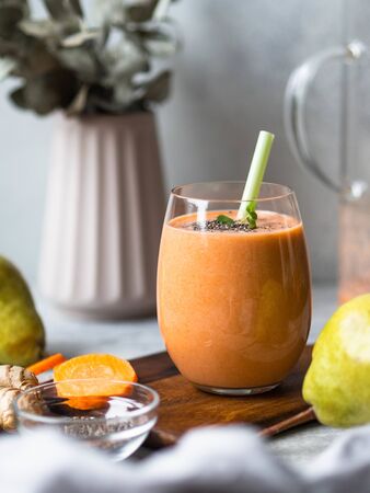 Glass of fresh healthy carrot, pear, ginger smoothie with chia seeds on a grey backgroundの写真素材