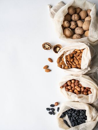 Reusable eco-friendly fabric bags for storage or shopping with various nuts and raisins on a white background.の写真素材