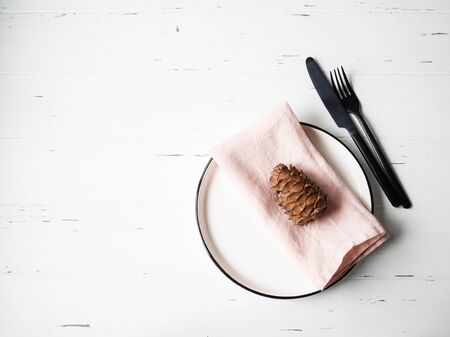 Rustic table setting with plate, pink napkin, eucalyptus and appliances on white wood table.の写真素材