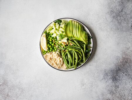 Quinoa bowl with green beans, green peas, cucumber, avocado, and pine nuts on grey background. Top viewの写真素材