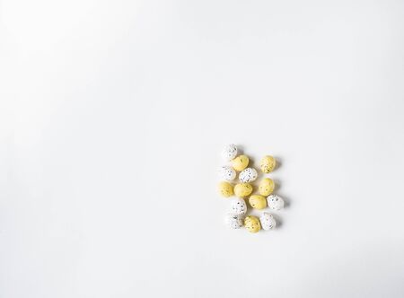 Female hands holding a handful of Easter yellow and white eggs on a white background. Top view.