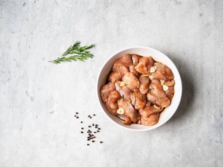 Raw diet marinated turkey meat with garlic, ginger and teriyaki sauce in a white bowl. Marinating meat for cooking barbecueの写真素材