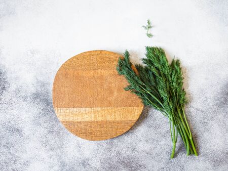 wood round cutting board and fresh dill on gray background. Top view. Copy spaceの写真素材