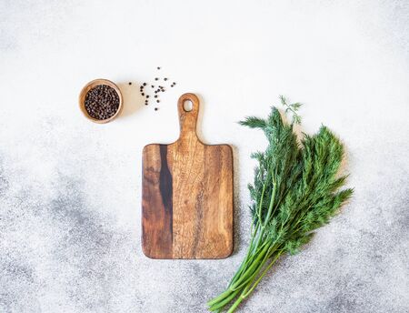 Wooden cutting board mock up, spices in a wooden bowl and fresh dill on a grayの写真素材