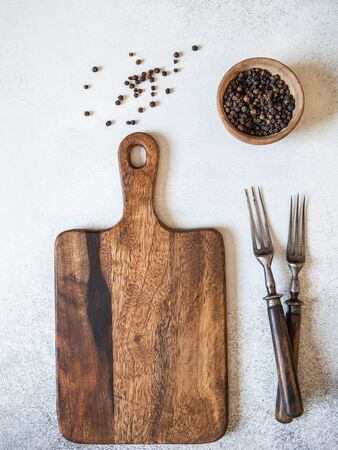 Wood cutting board mock up, spices in a wooden bowl and two vintage forks on a gray background. Top view. Copy spaceの写真素材