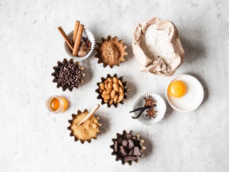 Baking ingredients: flour, brown sugar, egg, cocoa, almond, dark chocolate and spices on grey background. Top view.の写真素材