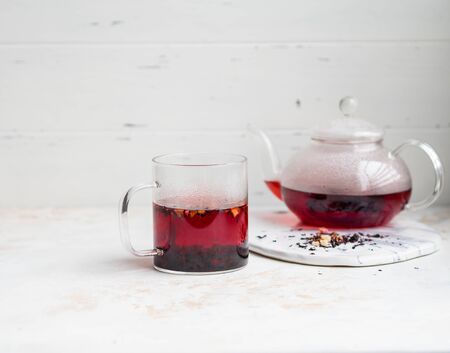 Glass transparent mug with purple hot hibiscus tea with slices of various dried fruits and berries isolatedの写真素材
