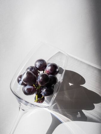Wine concept. A bunch of dark purple grapes in wine glass on a white background. Top viewの写真素材