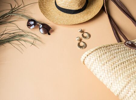 Women's summer straw hat, wicker bag, sunglasses and jewelry on beige background. Copy spaceの写真素材