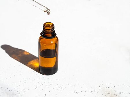 Brown glass with a dropper and a drop of essence. Bottle mockup cosmetic oil dropper on glass pipette. Copy spaceの写真素材