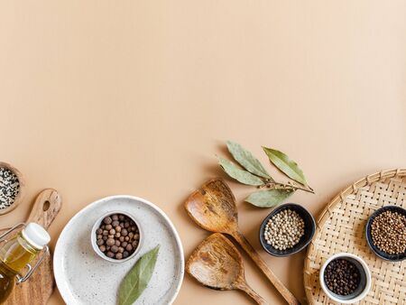 Flat lay of small bowls various dry spices, wood kitchen utensils, olive oil in glass bottle on a beige background. Top view. copy spaceの写真素材