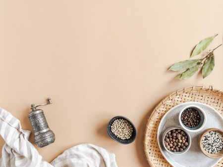 Kitchen flat lay of small bowls various dry spices, napkin and metal spice mill on beigeの写真素材