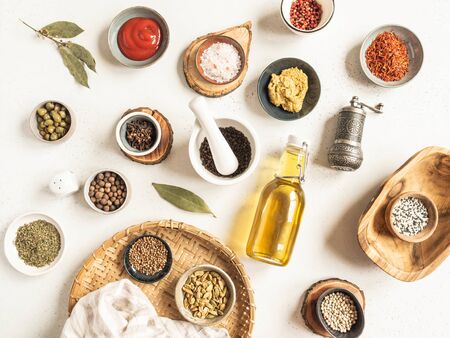 Various dry spices and sauces on a light background. Flat lay of small bowls with dijon mustard, olive oil, ketchup, capers and spices. Top viewの写真素材