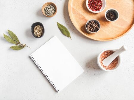 Kitchen notepad mock up for culinary text and various spices in bowl and sea salt in white mortar on white background. Top viewの写真素材