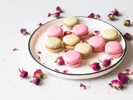 Sweet macaron cookies on plate and dry flowers on whiteの写真素材