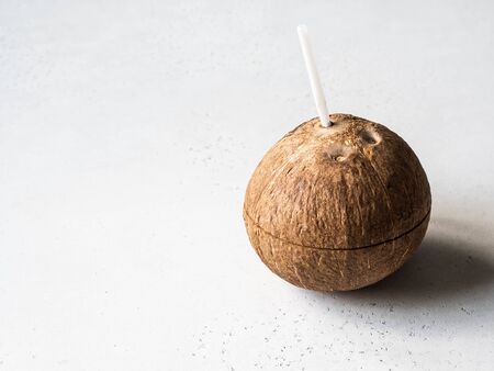 Drinking coconut with inserted white cocktail straw on a whiteの写真素材