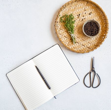 Kitchen background with open cookbook for recipes and various spices and herbs on a light background. Top view. Copy spaceの写真素材