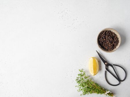A bunch of fresh green garden thyme, slice of lemon, black scissors and black pepper in bowl on light background. Top view. Copy spaceの写真素材
