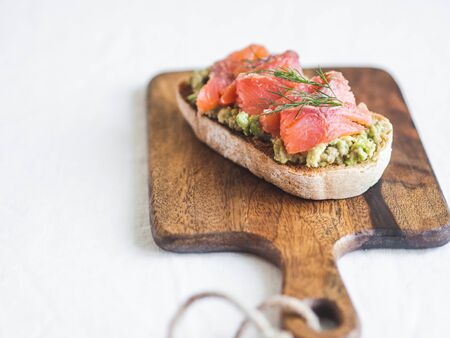 Avocado and smoked salmon toast on wood cutting board. Healthy food concept. Top view. Copy spaceの写真素材