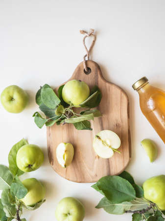 Homemade apple cider vinegar in glass bottle. Fermented apple juice and fresh apples and leaves on...