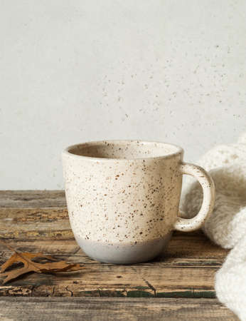 Two-tone mottled cup with a drink and a knitted blanket on an old wooden table. Copy spaceの写真素材