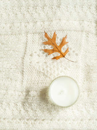 Autumn composition. Frame made of knitted plaid or scarf, scented candle and fallen leave. Autumn, fall concept. Flat lay, top view, copy space.の写真素材