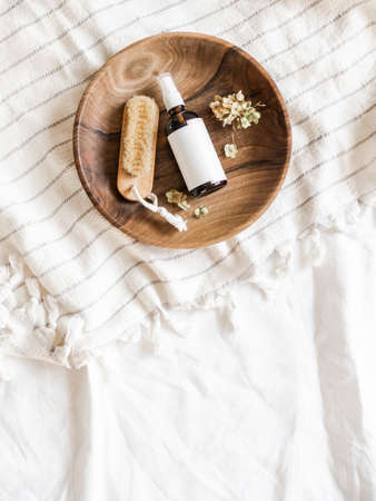 Skin care mockup brown bottle and wooden brush in a bowl on a towel in bathroom, flat lay. top view, copy spaceの写真素材