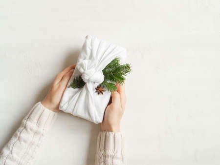 Woman hands hold Christmas reusable sustainable gift. Christmas reusable sustainable gift wrapping...