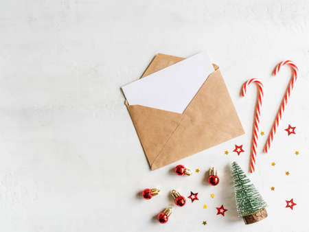 Empty card in craft envelope and various christmas decor on texture white background Holiday and invitation mockup.の写真素材