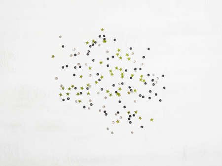 Multicolored sequins and green stars on a textured white background. Festive concept. Perfect background for your design.の写真素材