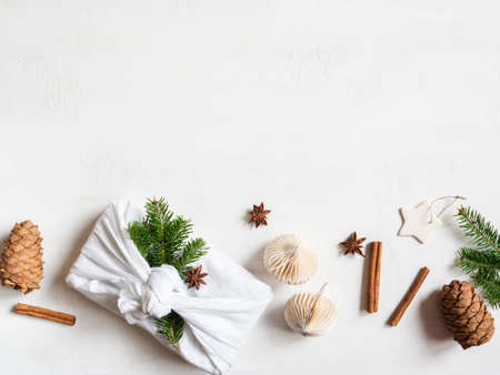 Flat lay fabric wrapped gift with fir tree branch and nature decor. Christmas reusable sustainable gift wrapping alternative. Zero waste concept. Copy space. Top view.の写真素材