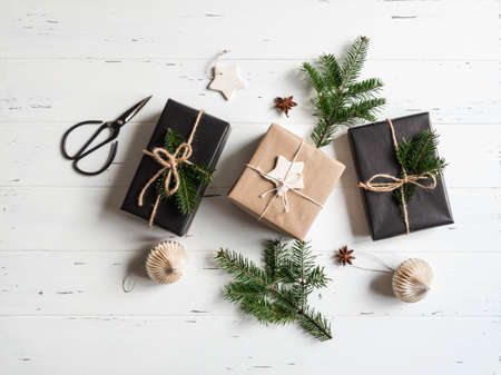 Flat lay of Christmas gifts sustainable packed. Christmas packaging in natural and black colors on a white wooden background. Top view. Copy spaceの写真素材