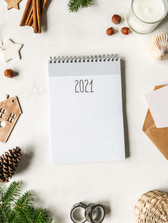Frame of various Christmas decor and notebook with the inscription 2021 on white background. Top view. Copy spaceの写真素材