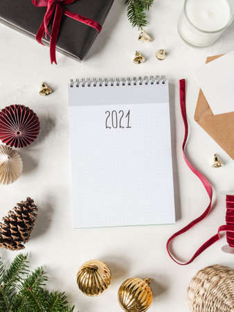 Frame of various Christmas decor and notebook with the inscription 2021 on white background. Top view. Copy spaceの写真素材