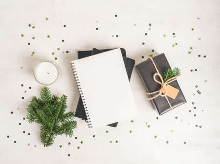 Flat lay of various Christmas decor and notebook with blank page and confetti on white textured background. Top view. Copy spaceの写真素材